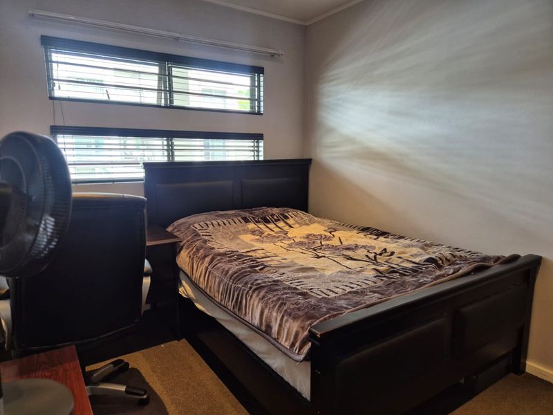 A bedroom featuring horizontal venetian blinds and neutral wall finishes, providing a functional space with natural light.