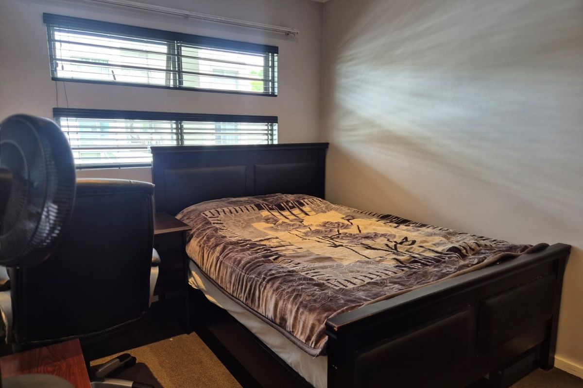 A bedroom featuring horizontal venetian blinds and neutral wall finishes, providing a functional space with natural light.