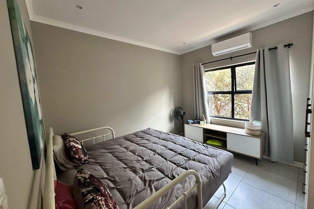 A well-maintained bedroom featuring neutral wall tones, tiled flooring, recessed lighting, and a wall-mounted split-system air conditioning unit.