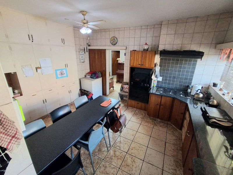 A functional kitchen featuring built-in cabinetry, granite countertops, a gas hob with extractor, and an eye-level oven, with tiled flooring throughout.