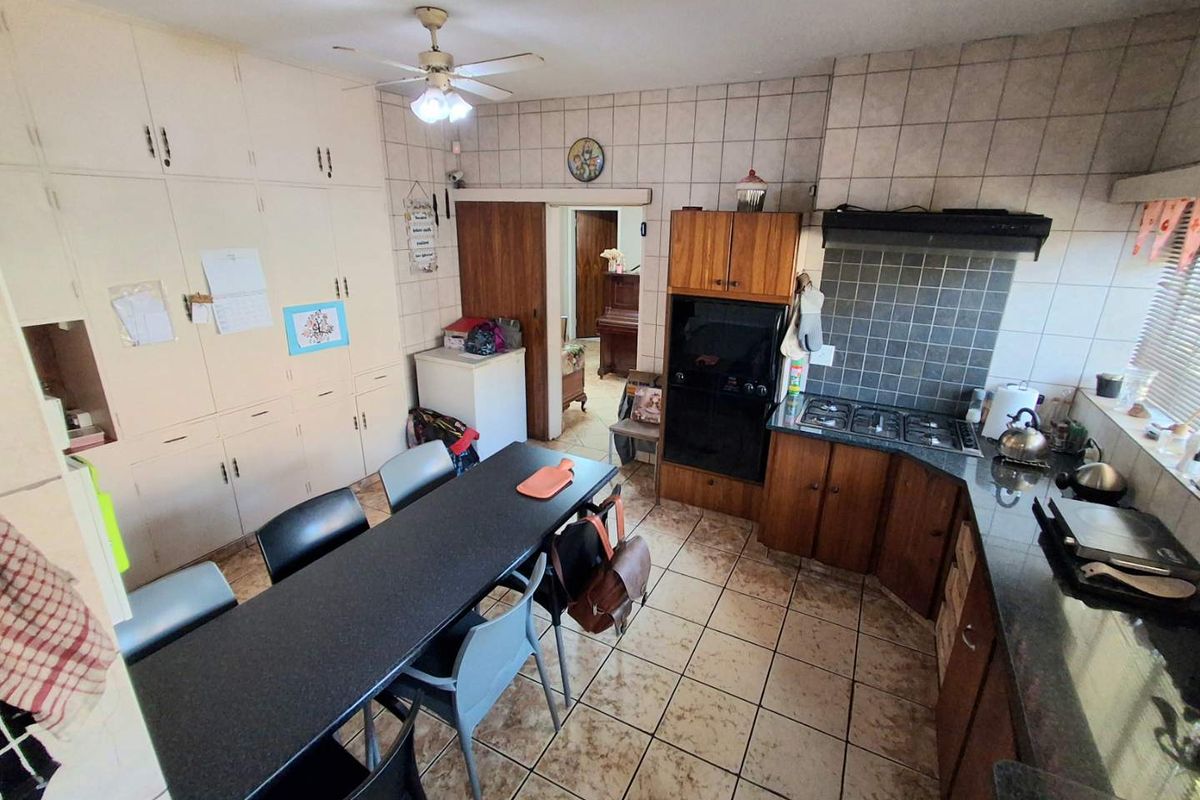 A functional kitchen featuring built-in cabinetry, granite countertops, a gas hob with extractor, and an eye-level oven, with tiled flooring throughout.