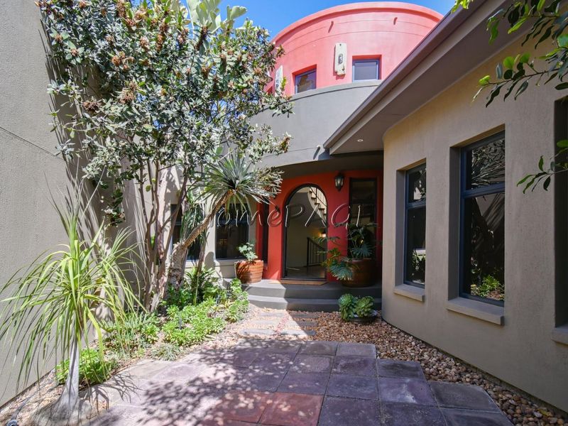 A welcoming front entrance featuring an arched doorway, paved pathway, and landscaped garden area with modern architectural design elements.