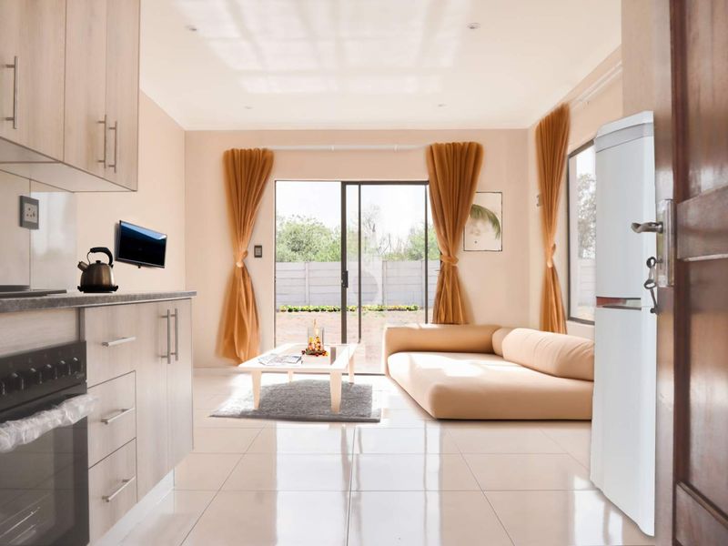 Modern open-plan living area featuring a functional kitchen with built-in cabinetry, electric stove, and seamless access to the outdoor patio through sliding glass doors.