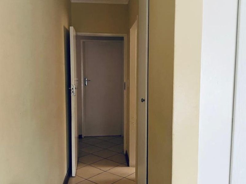 A functional hallway featuring tiled flooring and built-in storage cupboards, providing access to adjacent rooms within the apartment.