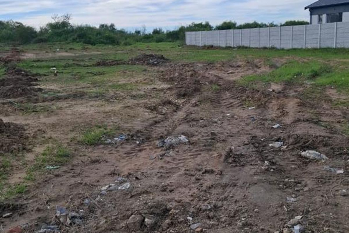 An undeveloped plot of land featuring uneven terrain and a precast concrete boundary wall, offering a blank canvas for future landscaping or development.