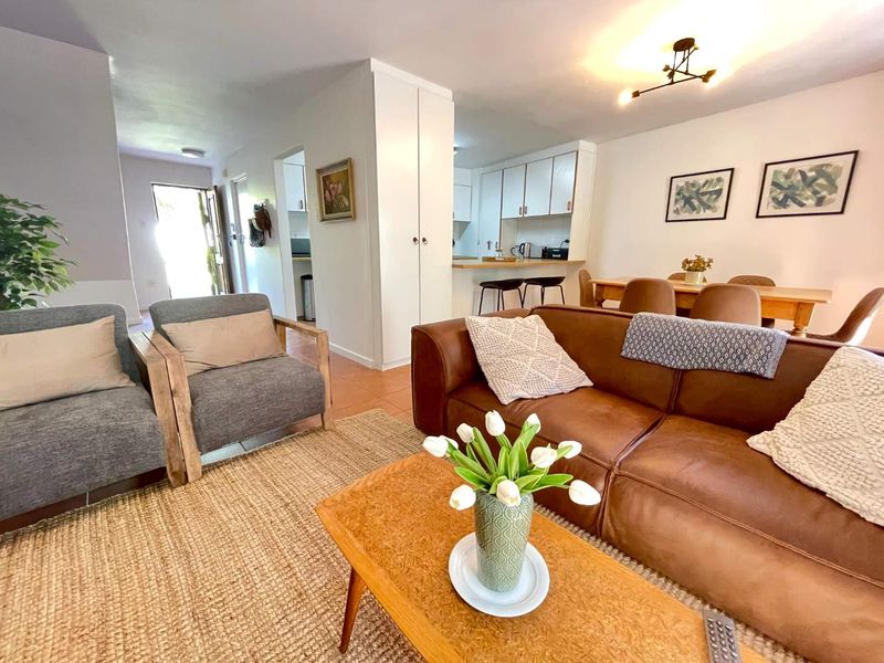 Open-plan living and dining area featuring tiled flooring, a breakfast bar, and built-in kitchen cabinetry, creating a functional and connected living space.