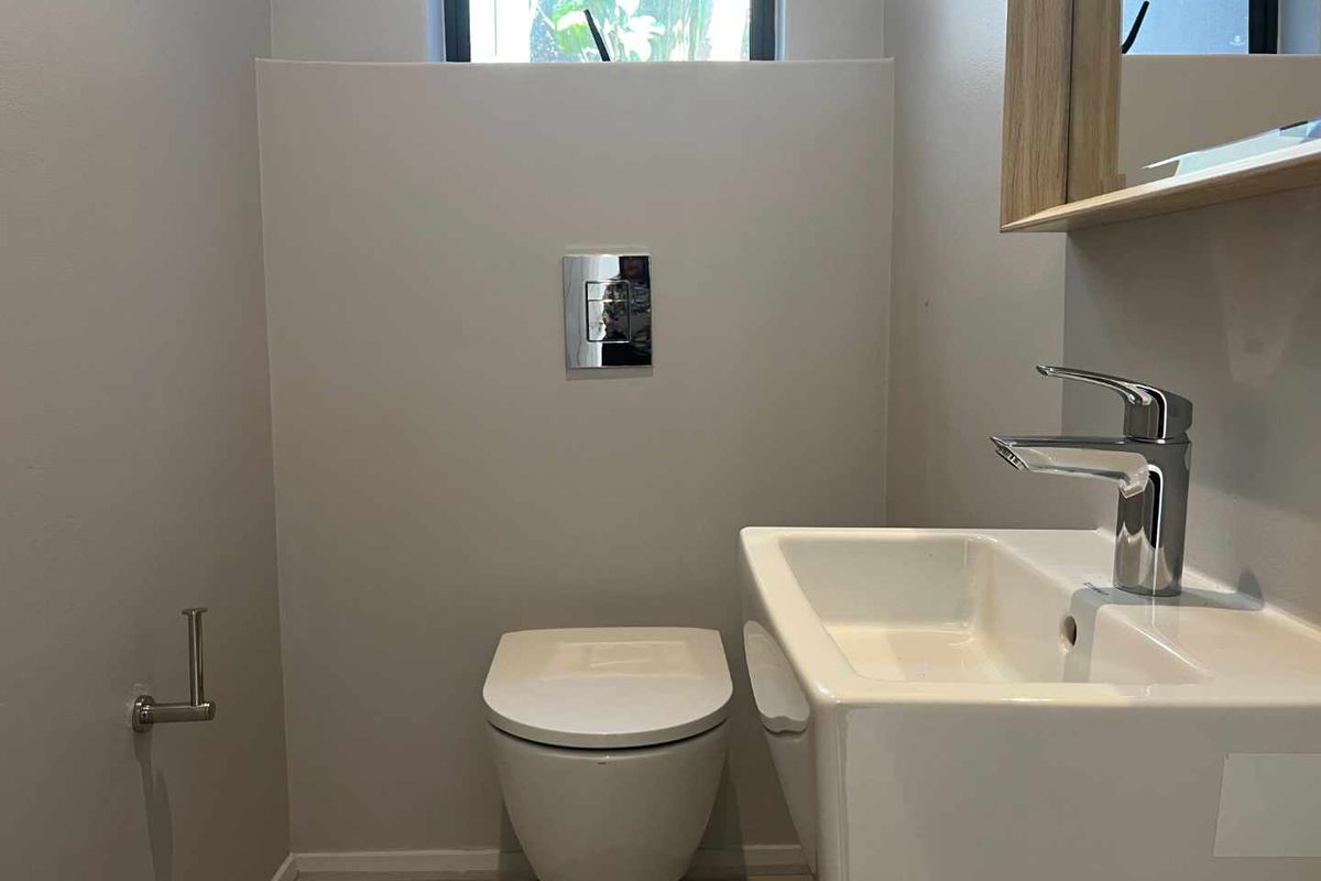 A modern, minimalist guest bathroom featuring a wall-hung toilet with a concealed cistern and a sleek wall-mounted basin.