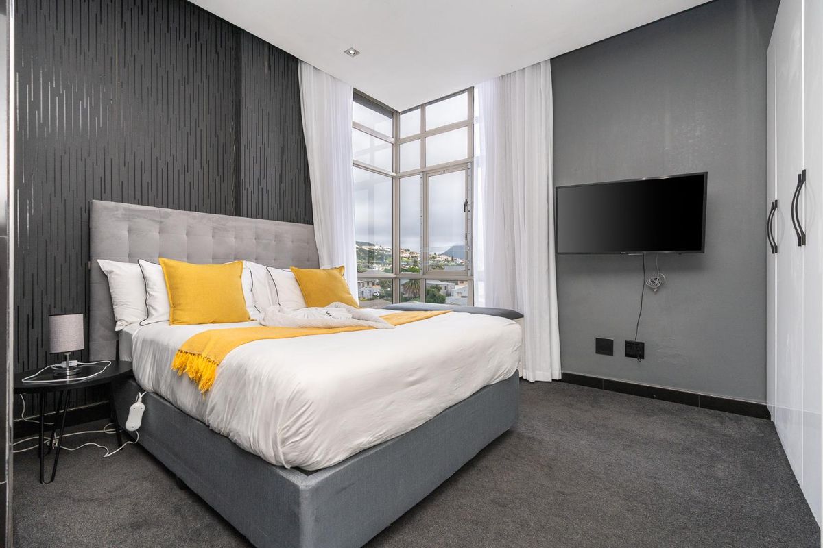 Modern bedroom featuring a textured feature wall, corner windows with natural light, carpeted flooring, and a built-in wardrobe.