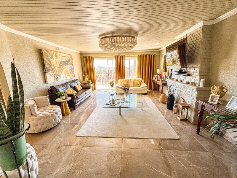 Spacious living room featuring large format floor tiles, a brick fireplace, and sliding glass doors leading to an outdoor balcony with scenic views.