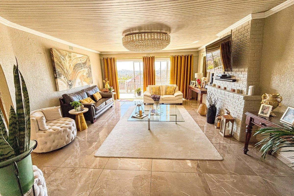 Spacious living room featuring large format floor tiles, a brick fireplace, and sliding glass doors leading to an outdoor balcony with scenic views.