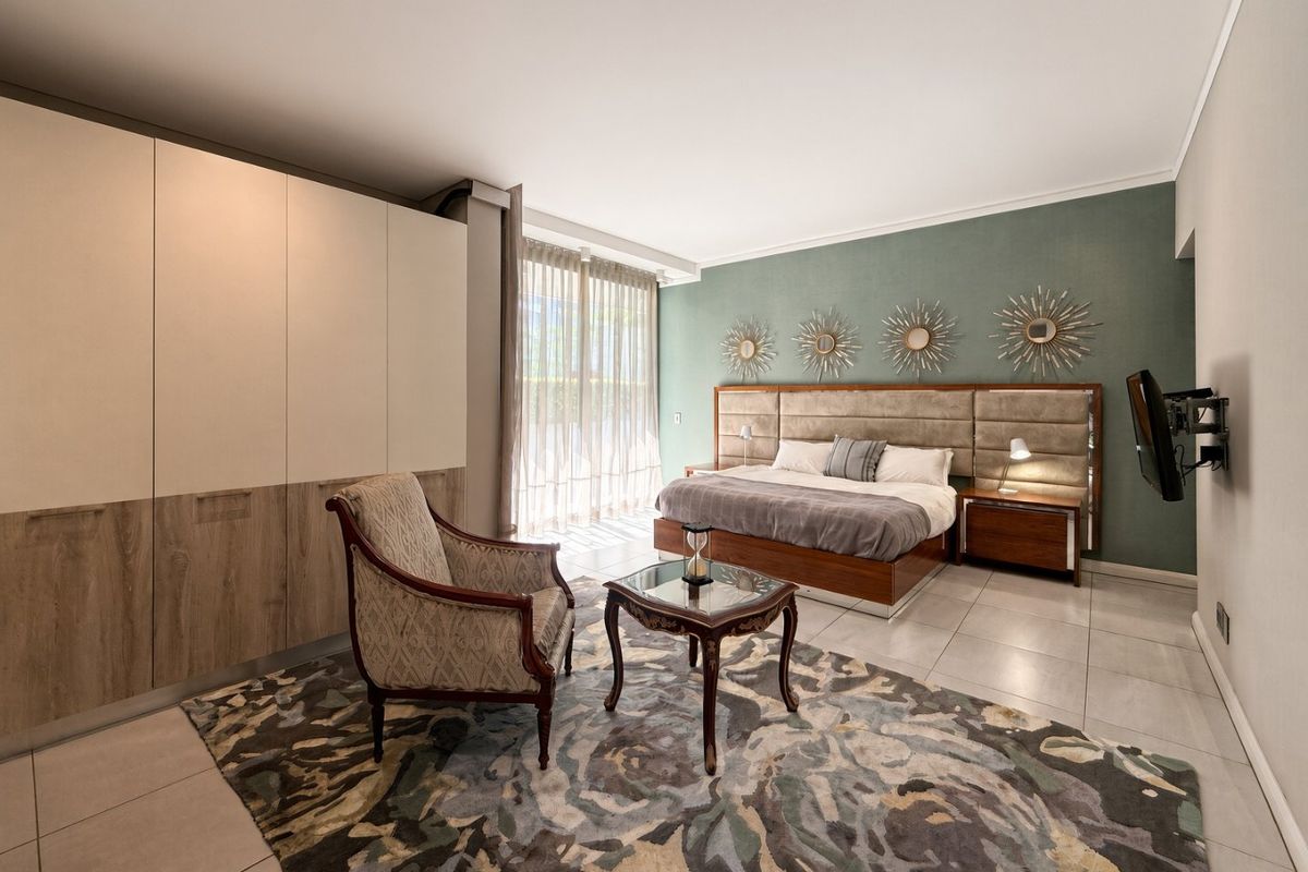 Spacious bedroom featuring large built-in cupboards, tiled flooring, and a sliding glass door providing natural light.