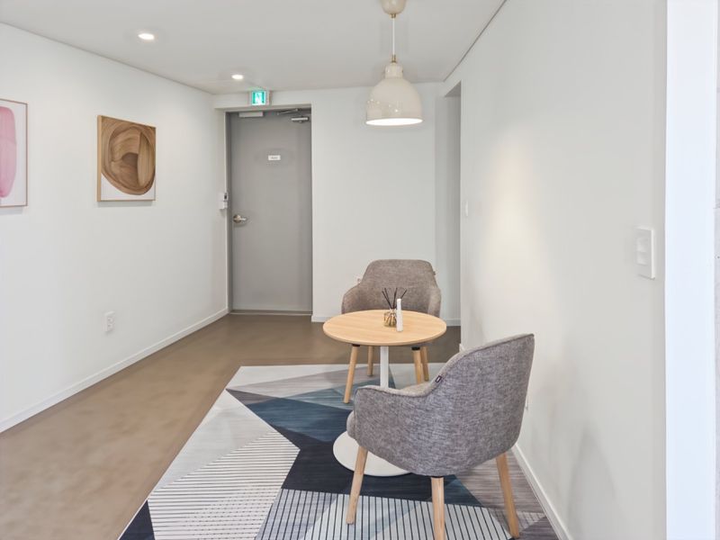 A bright and modern office breakout area featuring clean white walls, recessed lighting, and a contemporary pendant light fixture.