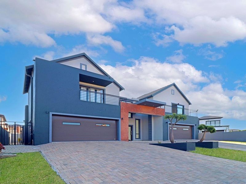 Modern double-story residential property featuring a paved driveway, double garage, and upper-level balcony with contemporary architectural finishes.