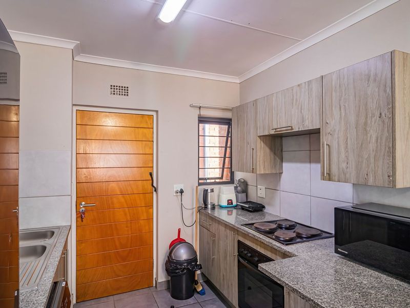 A functional kitchen featuring wood-look cabinetry, granite countertops, a built-in oven and hob, and a stainless steel sink.