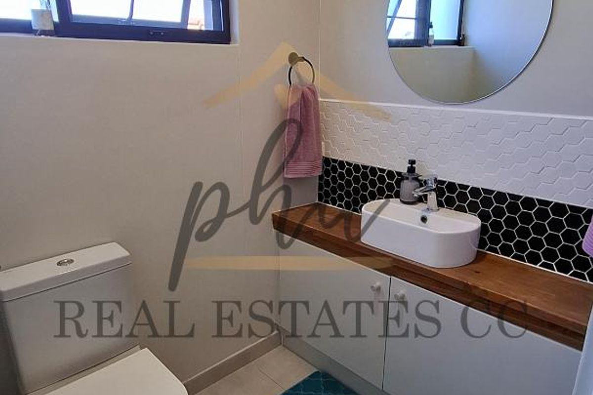 Modern bathroom featuring a vessel sink on a wooden vanity, hexagonal tile backsplash, and a contemporary toilet.