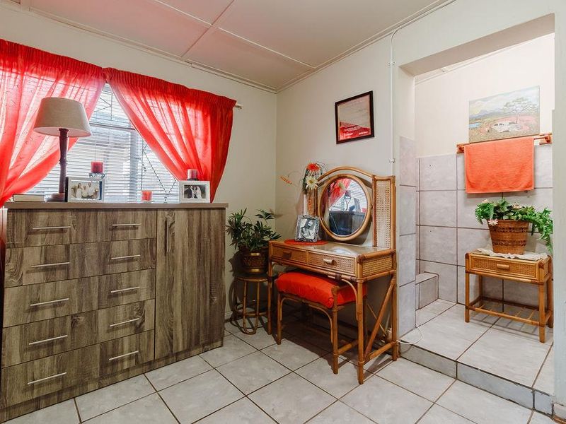 A bedroom featuring tiled flooring and an integrated tiled shower area, offering a functional layout with potential for modern updates.