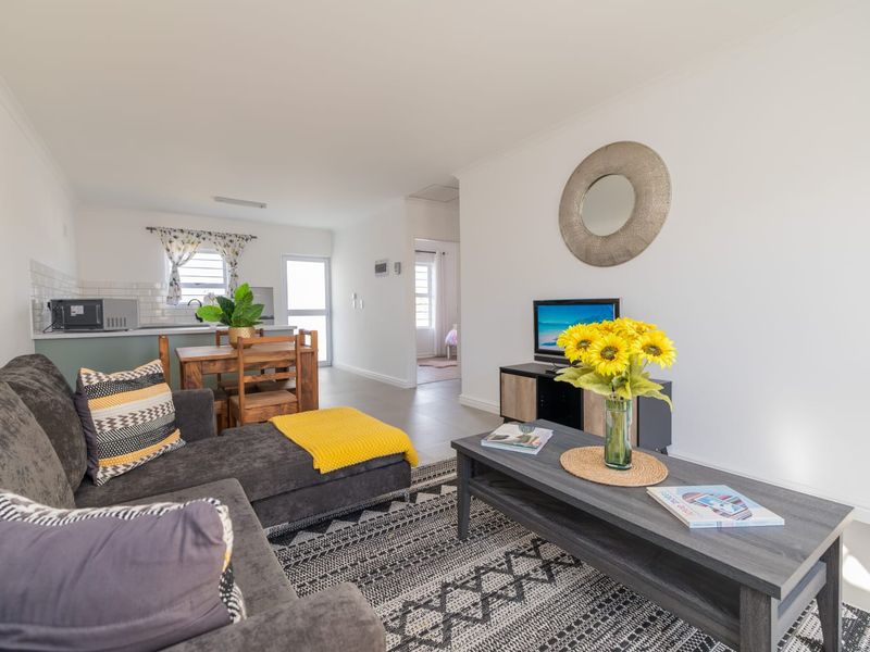 An open-plan living and kitchen area featuring neutral tiled flooring, modern cabinetry, and a subway tile backsplash, creating a bright and functional living space.