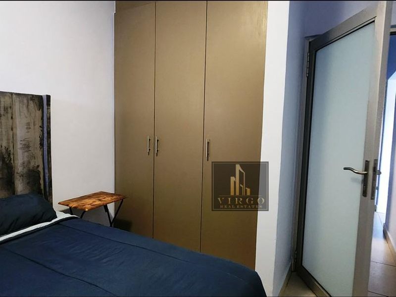A bedroom featuring built-in cupboards and a frosted glass door leading to an adjacent hallway.