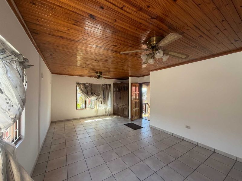 Spacious living area featuring ceramic tiled flooring, a timber tongue and groove ceiling with dual ceiling fans, and built-in wooden storage cabinetry.