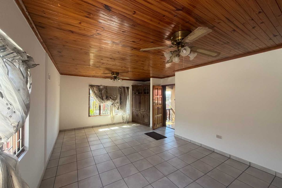 Spacious living area featuring ceramic tiled flooring, a timber tongue and groove ceiling with dual ceiling fans, and built-in wooden storage cabinetry.