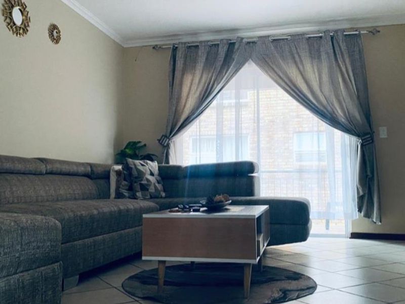 A comfortable living room featuring tiled flooring and a sliding glass door that provides natural light and access to the exterior.