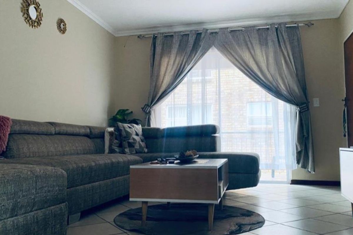 A comfortable living room featuring tiled flooring and a sliding glass door that provides natural light and access to the exterior.