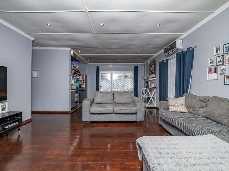 Spacious living room featuring dark hardwood flooring, recessed lighting, and a split-system air conditioner, with direct access to the outdoor area via sliding glass doors.