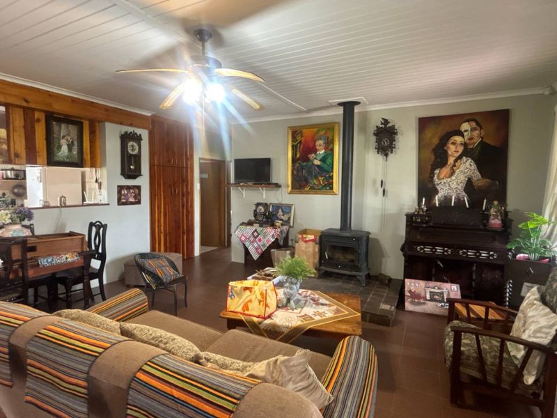 Spacious open-plan living area featuring a wood-burning stove, timber-clad ceiling, and tiled flooring, offering a warm and functional layout.
