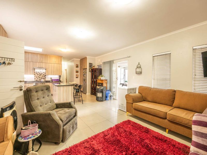 Open-plan living area featuring tiled floors, a modern kitchen with built-in cabinetry and an island, and direct access to the outdoor space.