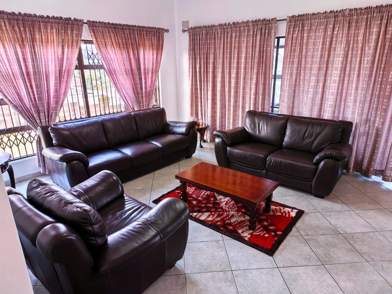 A spacious living room featuring tiled flooring and large windows fitted with security bars, offering a bright and functional living space.