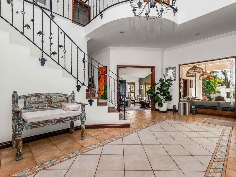Spacious grand entrance hall featuring a decorative tiled floor, wrought iron staircase railing, and an open-plan flow into the living areas.