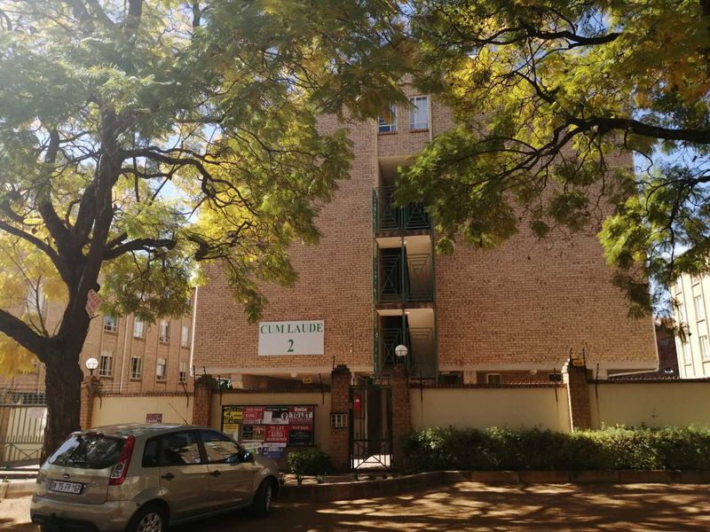 Front elevation of the Cum Laude 2 apartment complex, featuring a face brick facade, secure perimeter wall, and external stairwell access.
