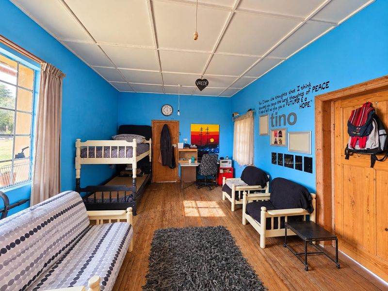 A bedroom featuring timber flooring and a tiled ceiling, offering a functional space with potential for cosmetic updates to modernize the interior.
