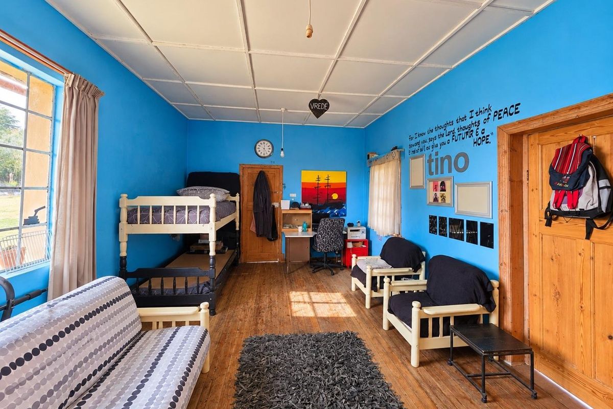 A bedroom featuring timber flooring and a tiled ceiling, offering a functional space with potential for cosmetic updates to modernize the interior.