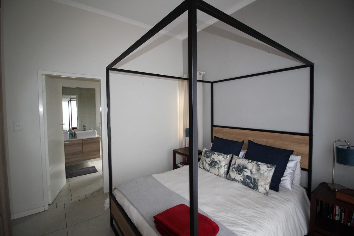 A well-maintained bedroom featuring tiled flooring and an en-suite bathroom with a modern vanity unit.