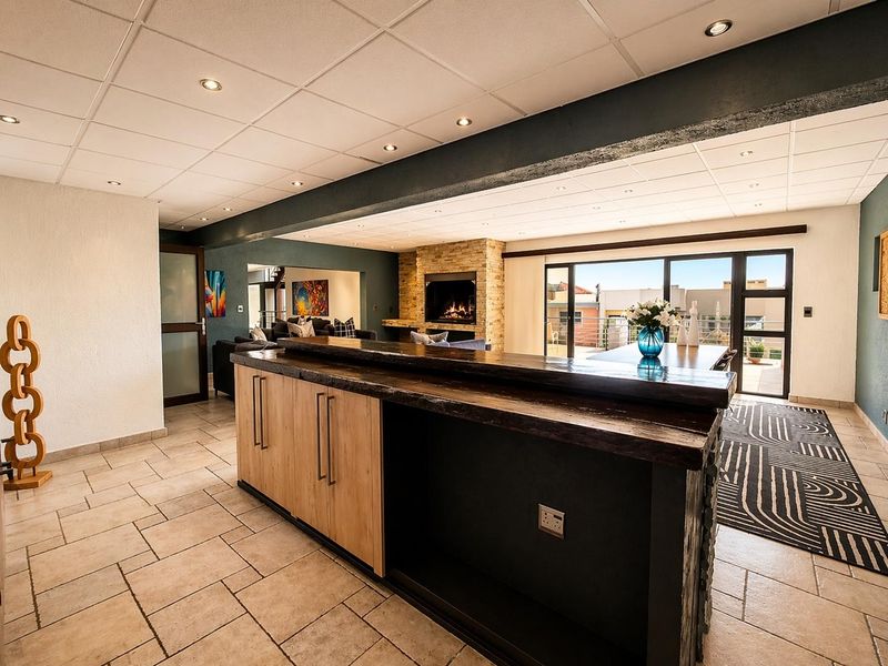 Spacious open-plan living area featuring a built-in bar, stone-clad fireplace, and large sliding glass doors leading to an outdoor space.