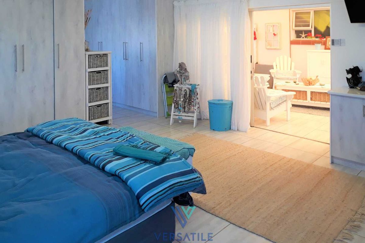 Spacious bedroom featuring extensive built-in cabinetry and tiled flooring, with an adjoining sunroom or seating area accessible through a wide doorway.
