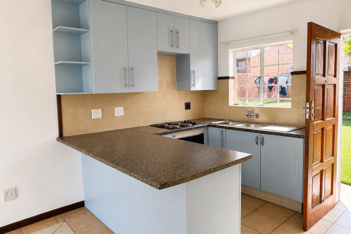 A functional kitchen featuring light blue cabinetry, laminate countertops, a built-in hob and oven, and tiled flooring with direct access to the exterior.