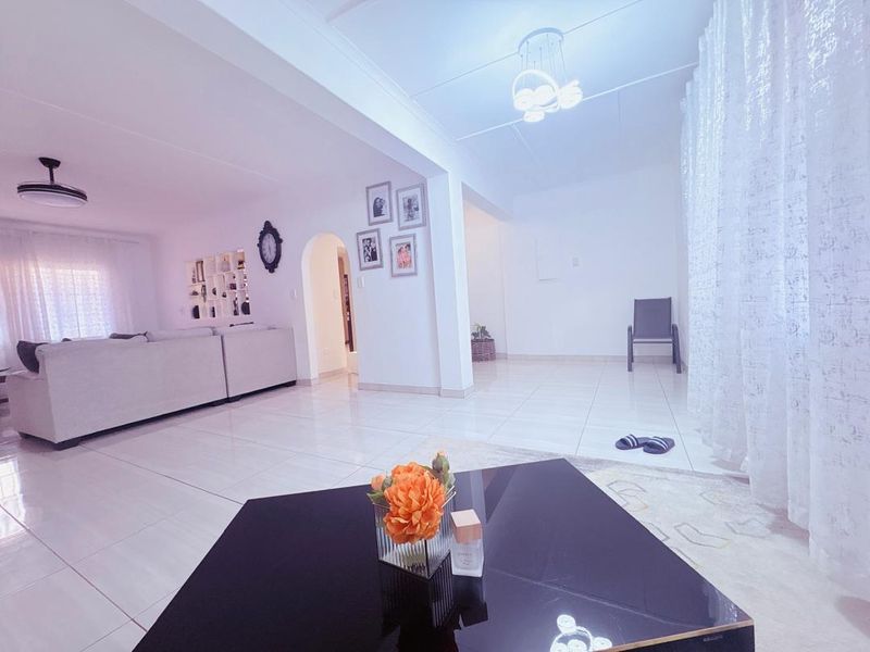 Spacious open-plan living area featuring neutral tiled flooring, an elegant archway, and modern lighting, creating a bright and versatile living space.