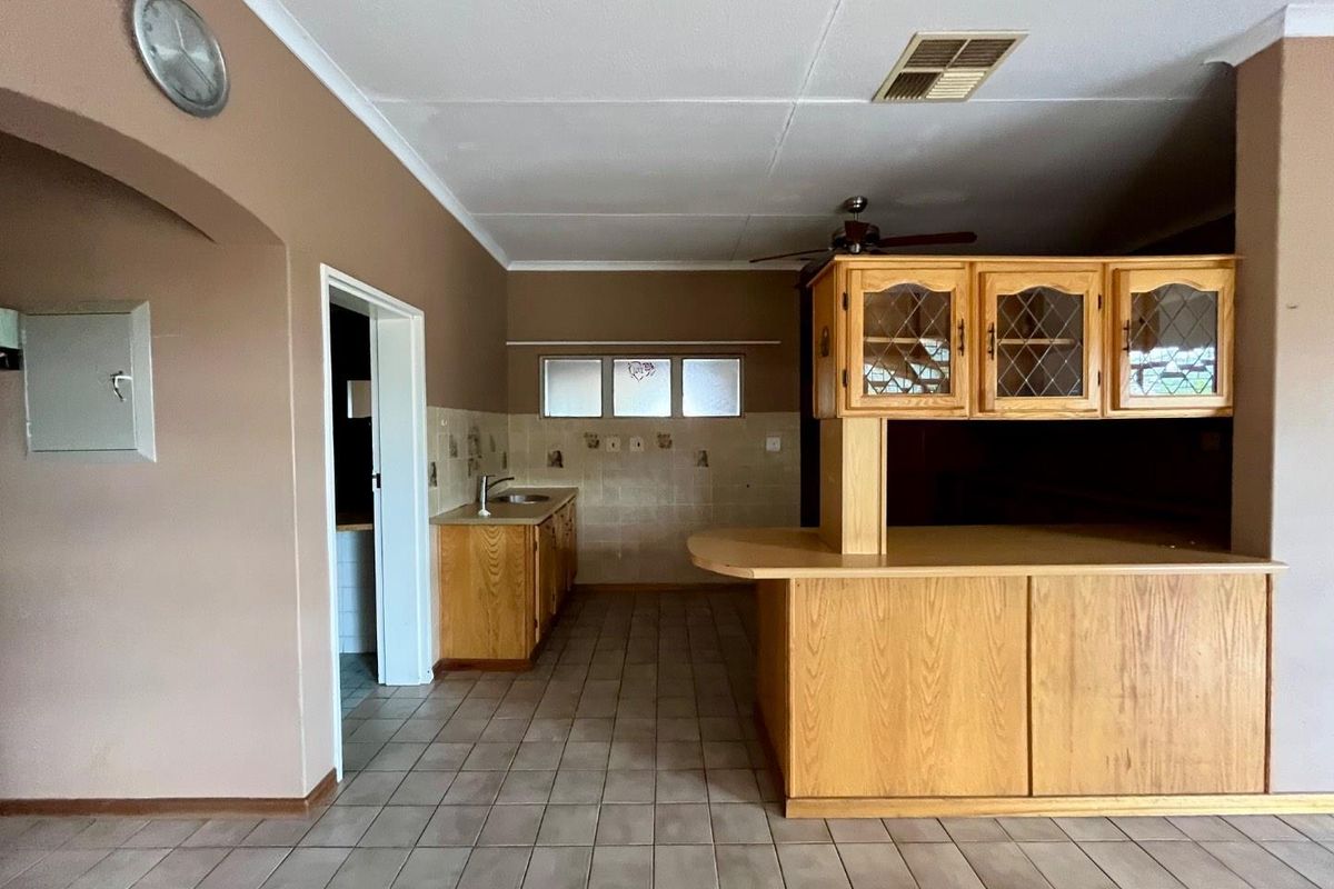 A dated kitchen area featuring wooden cabinetry, a breakfast bar, and tiled flooring, offering significant potential for a modern renovation and layout update.