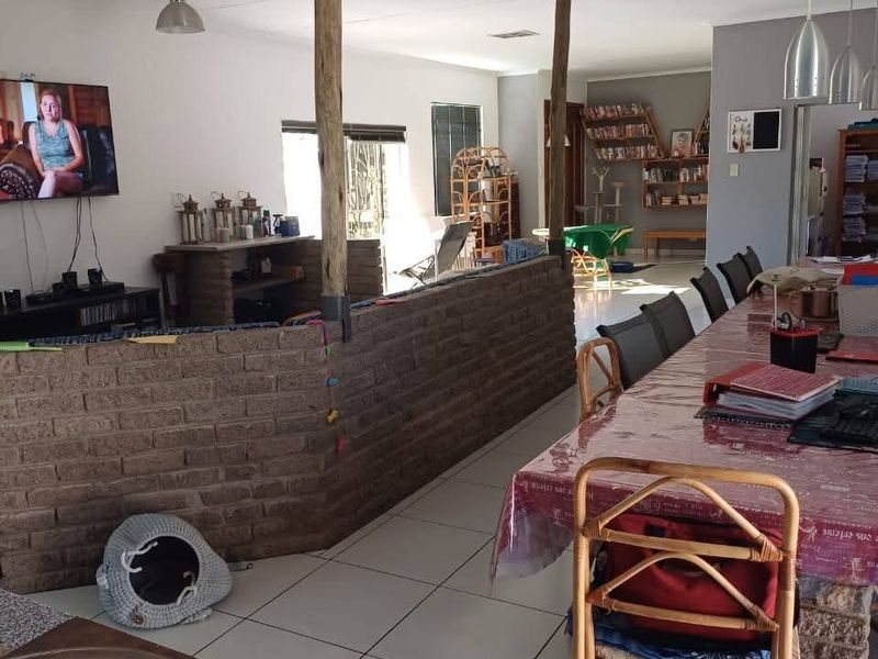 Spacious open-plan living and dining area featuring exposed brick partitioning, timber support posts, and neutral ceramic floor tiling throughout.