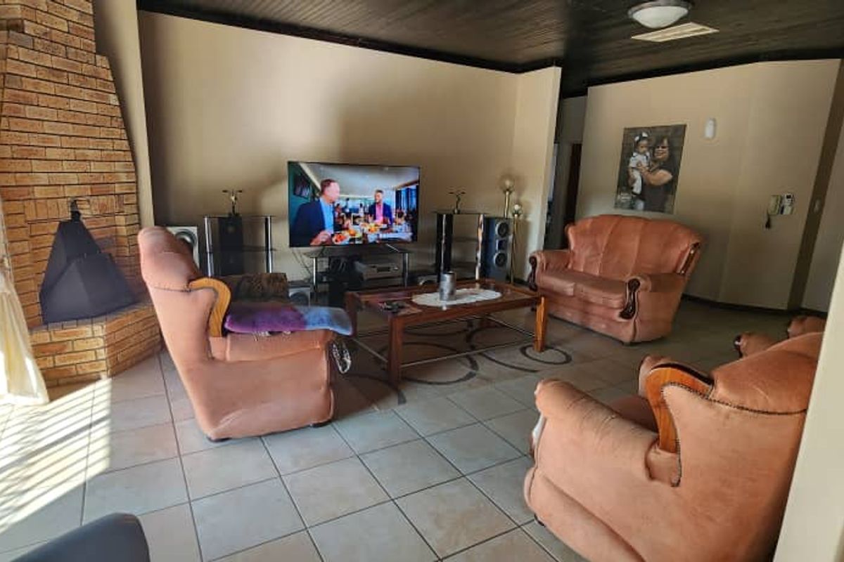 A spacious living room featuring a prominent brick fireplace, tiled flooring, and sliding glass doors providing access to the outdoor area.