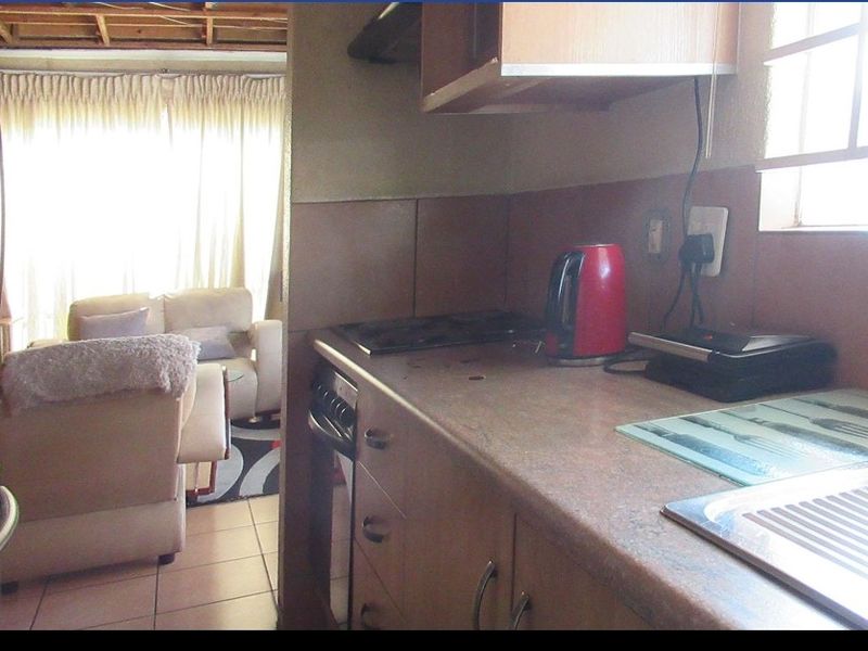 Compact kitchen featuring built-in cabinetry, laminate countertops, and a stainless steel sink, with direct access to the adjacent living area.