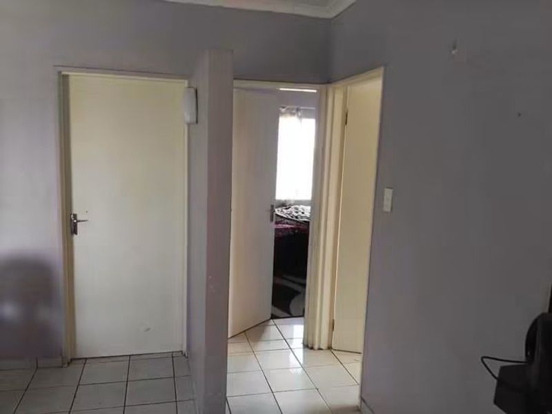 A functional hallway area featuring tiled flooring and multiple internal doors providing access to adjacent rooms.
