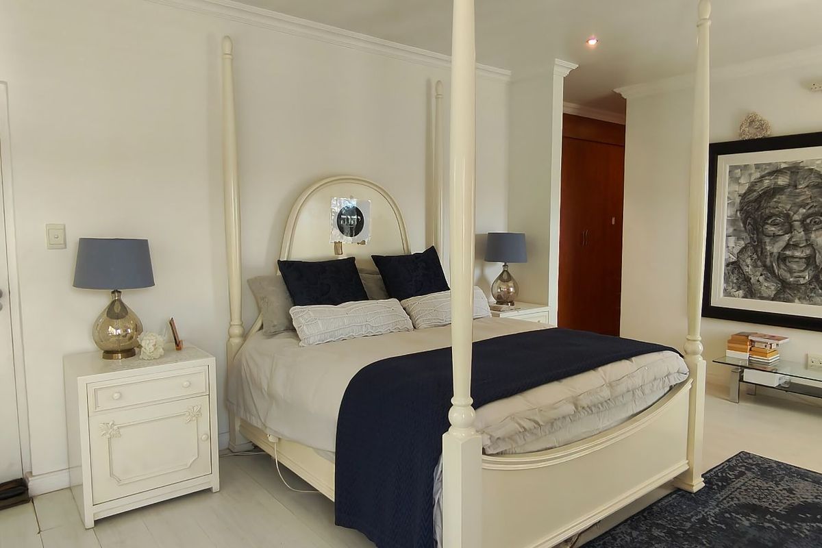Spacious bedroom featuring built-in cupboards, crown molding, and shutter blinds, offering a bright and well-maintained living space.
