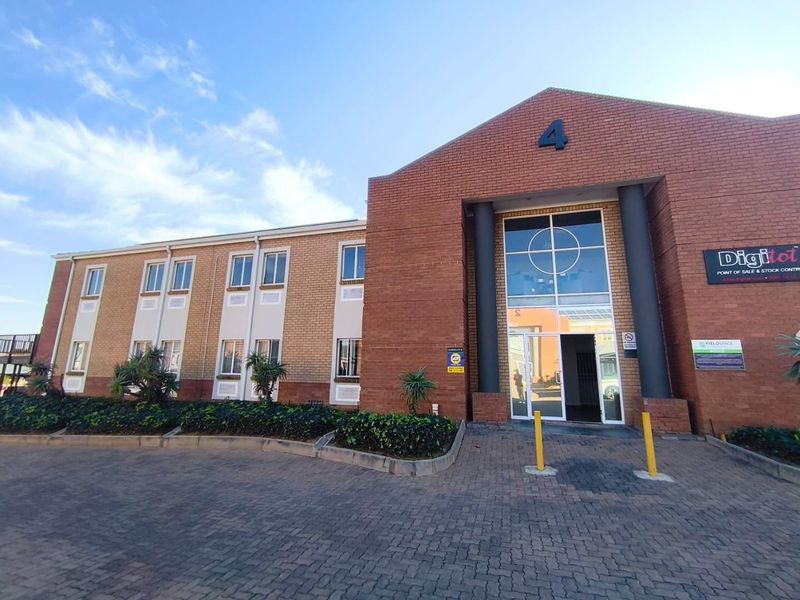 Front exterior view of a professional office building featuring a brick facade, paved driveway, and a prominent glass entrance.