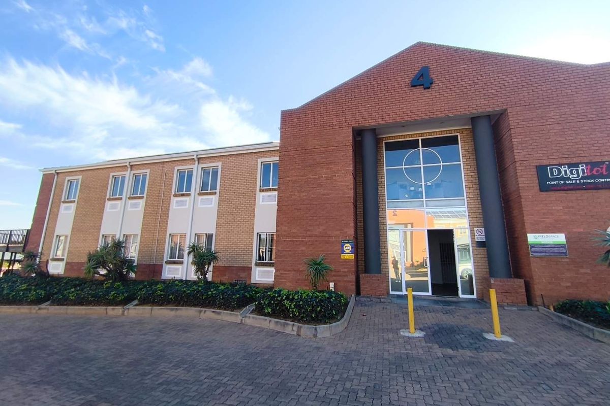 Front exterior view of a professional office building featuring a brick facade, paved driveway, and a prominent glass entrance.