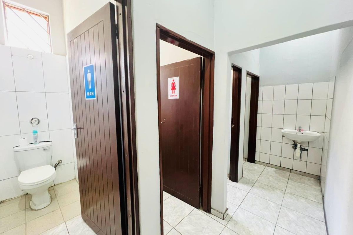 A functional commercial restroom facility featuring separate male and female entrances, tiled walls and floors, and a shared washbasin area.