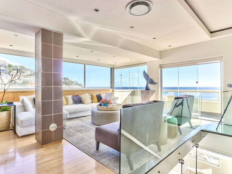 Spacious living area featuring hardwood floors, recessed lighting, and expansive glass doors offering panoramic ocean views and access to the balcony.