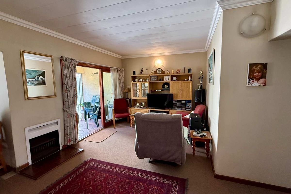 A comfortable living room featuring a built-in fireplace, crown molding, and sliding glass doors that open onto a private patio area.